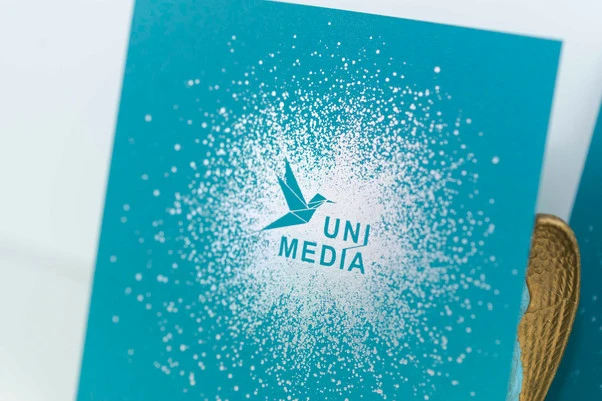 reflets laser sur papier bleu paon et logo oiseau origami avec typographie baton 