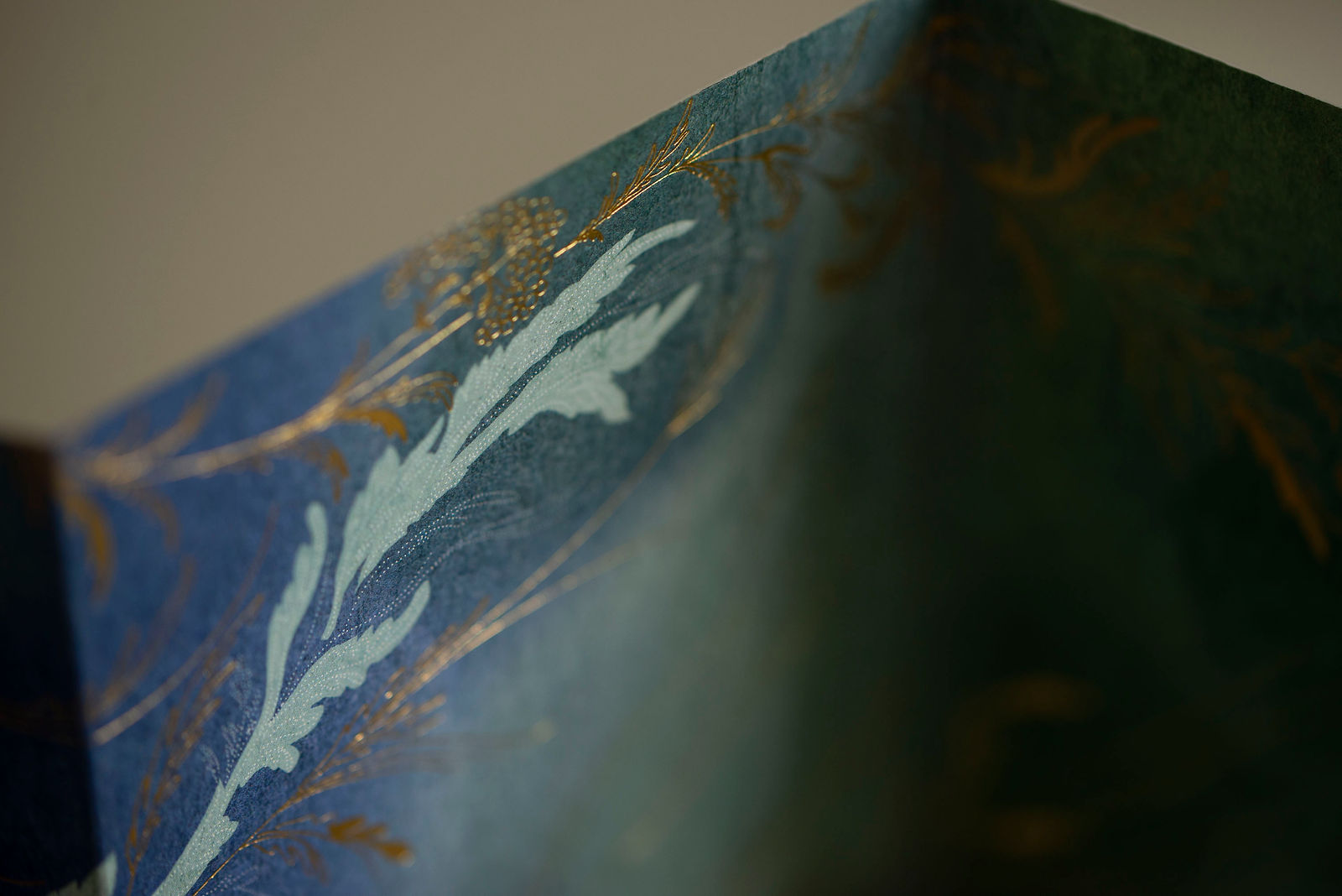 dépliant peint en bleu et vert avec motifs végétaux en dorure