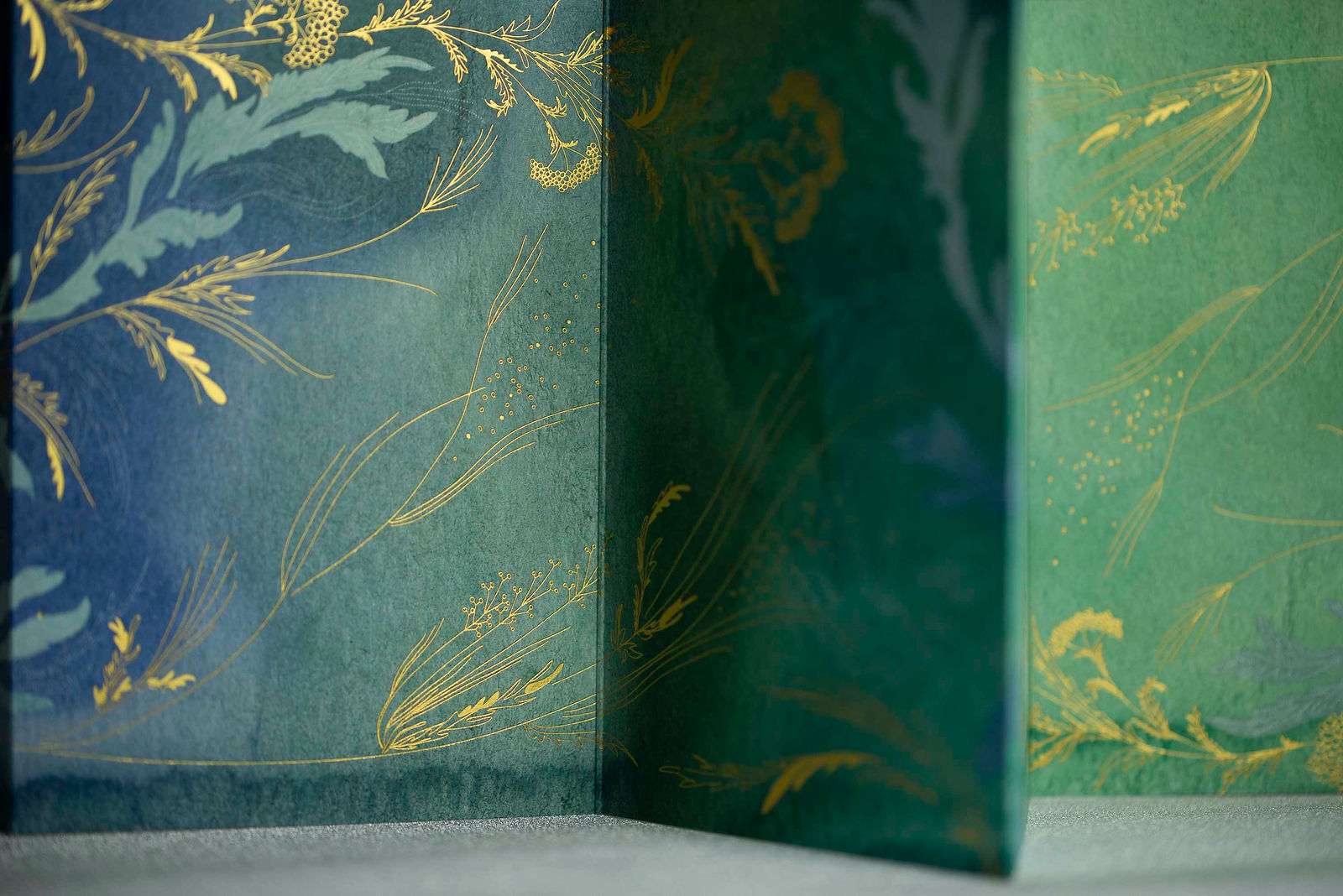 dépliant peint en bleu et vert avec motifs végétaux en dorure